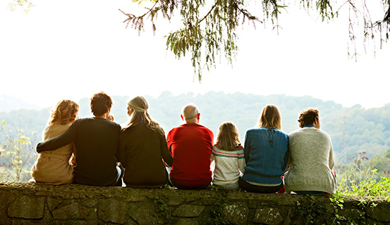 Mehrere Menschen sitzen auf einer Mauer und schauen in die Ferne